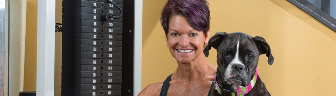 Smiling woman with dog in gym