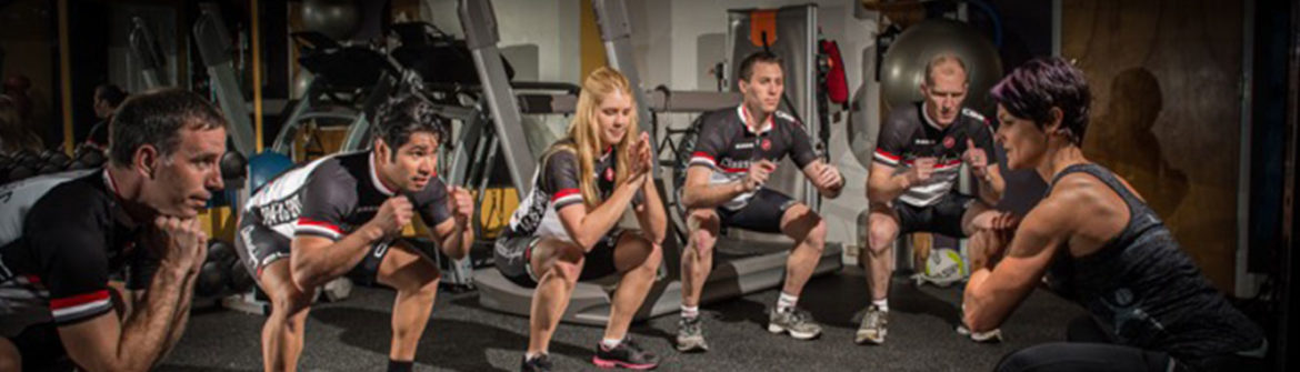 Trainer leading group doing squats in gym