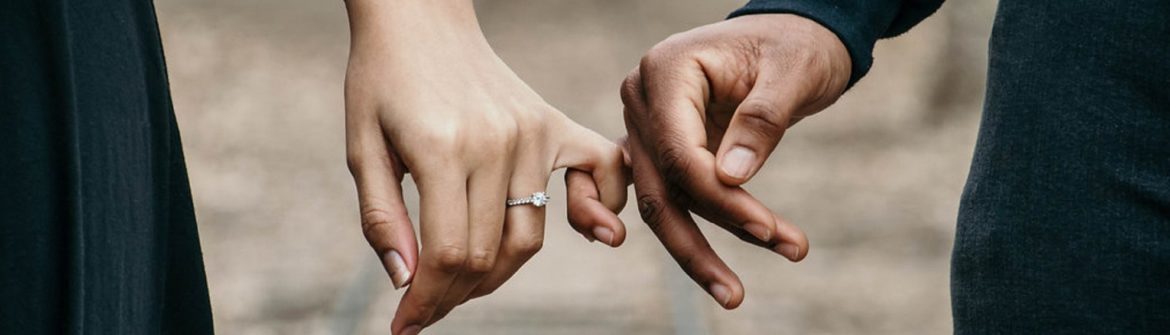 Close-up of two hands linking pinky fingers