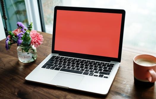 Open laptop with red screen, flowers, coffee