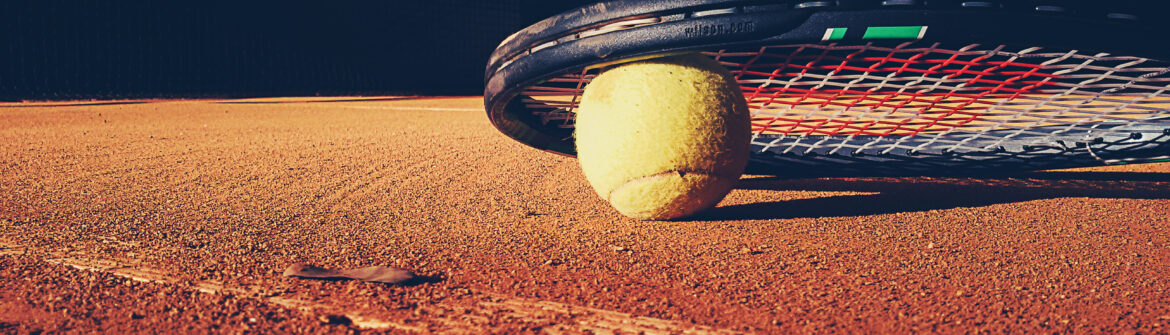 Tennis ball and racket on clay court