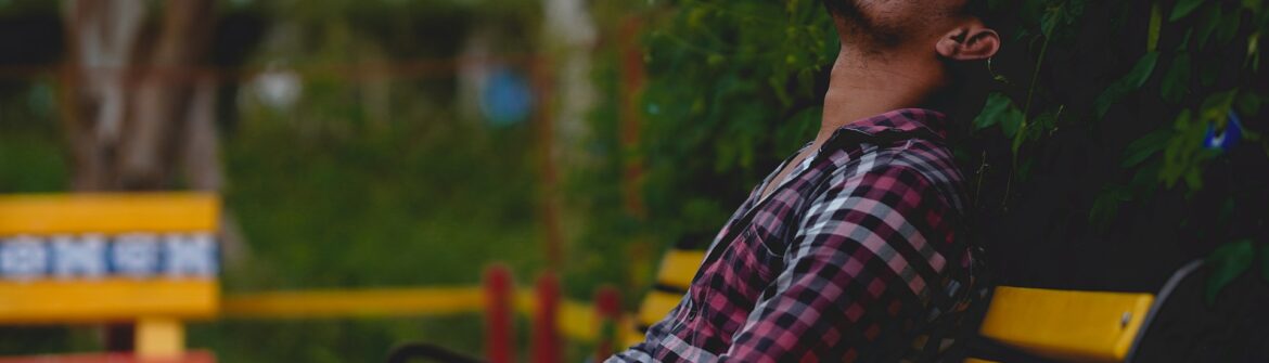 Man in plaid shirt resting on yellow bench